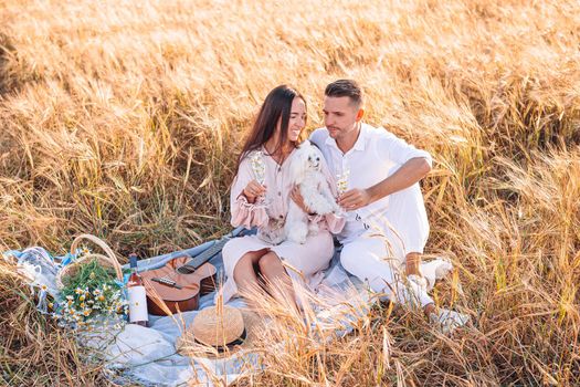 Guy with his girlfriend in love in the golden field. Young family on picnic in yellow wheat field
