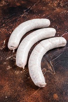 Raw German white sausage weisswurst on kitchen table. Dark background. Top view