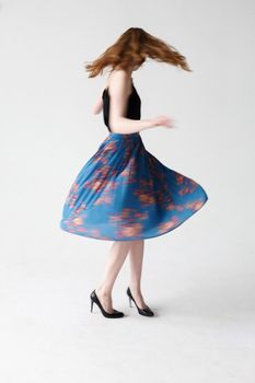 blurry movements of young caucasian skinny lady in blue skirt, indoors portrait