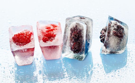 Ice cubes with frozen berries inside close up