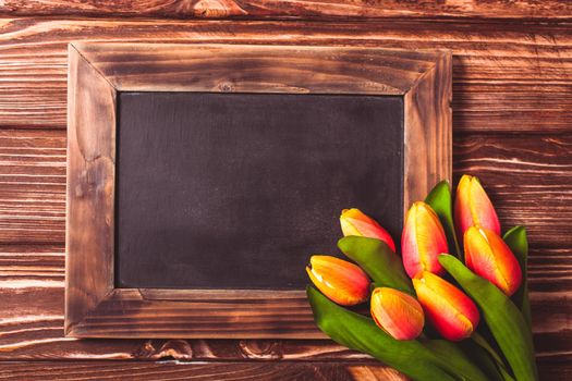 Tulips with chalkboard on a wooden background - spring greetings