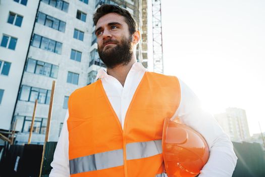 Builder wearing hardhat and safety vest standing on a commercial construction site