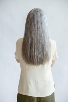 Lady with long loose silver hair stands on light grey background
