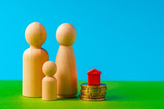 Wooden family with toy house and stack of coins. Savings for house purchase concept