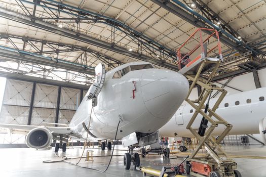 Big white plane in hangar during repair