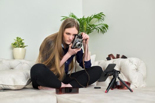 Young woman with vintage camera, photographic films, blogger recording stream