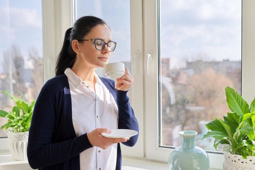 Beautiful business woman with cup of coffee near window, copy space