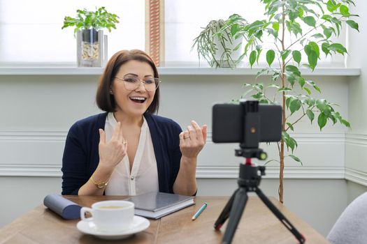 Video blog vlog stream, woman looking at smartphone webcam on tripod