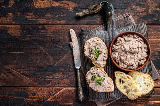 Toasts with Duck pate Rillettes de Canard on wooden board. Dark wooden background. Top View. Copy space