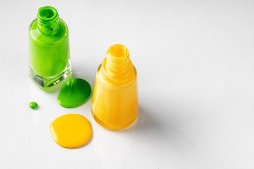 Bright colored nail polish bottles with drippings on white background