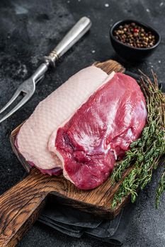 Duck breast fillet steaks, raw Poultry on wooden board. Black background. Top View