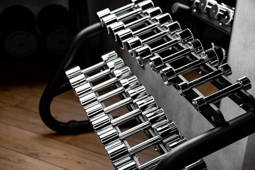 Rows of metal dumbbells on rack for bodybuilding in gym