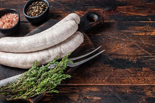 Munich traditional white sausages on a wooden board with thyme. Dark wooden background. Top view. Copy space