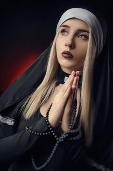 Fine art portrait of a novice nun in deep prayer with rosary