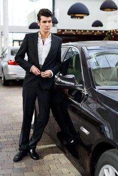 Young handsome man, model of fashion, with luxury cars