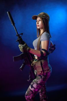 a woman in a military airsoft uniform in a vest with an American automatic rifle on a dark background