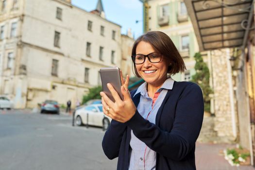 Middle-aged business woman in in cardigan glasses with mobile phone
