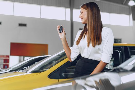 Young attractive woman buying a new car in car salon