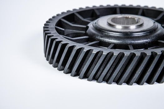 Black polymer gear camshaft with metal base. New spare part for an internal combustion engine on a gray background