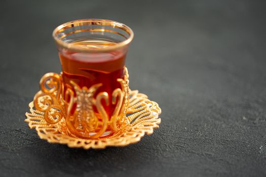 Turkish tea in traditional glass on black table