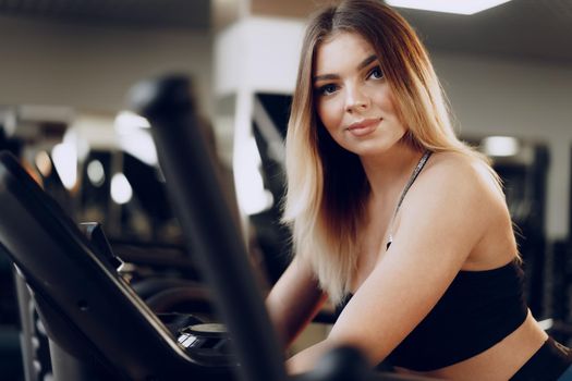 Fit curvy young blonde woman training in a cardio zone in a gym