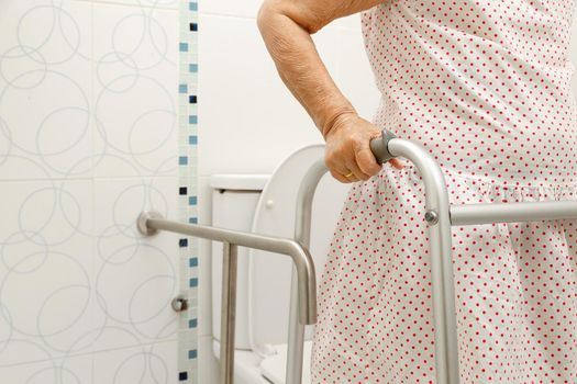 Elderly woman holding on walker in toilet.