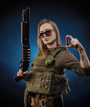 the girl in military overalls airsoft posing with a gun in his hands on a dark background