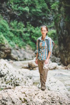 Explorer girl standing on rocky stone.
