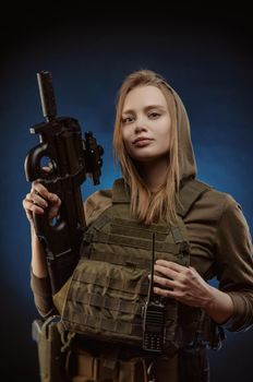 the girl in military overalls airsoft posing with a gun in his hands on a dark background