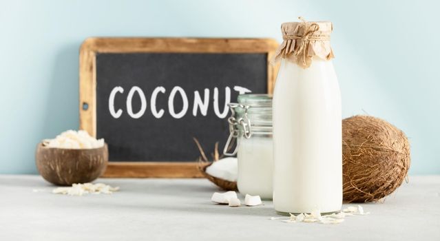Coconut products fresh coconut, oil, milk and chalkboard with Coconut lettering on blue background