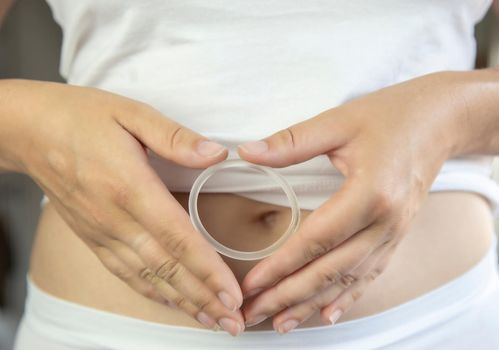 Birth control ,hormone, contraception ring in a womans hand white underwear and belly, vaginal ring for contraceptive use with copy space