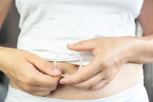 Birth control ,hormone, contraception ring in a womans hand white underwear and belly, vaginal ring for contraceptive use with copy space