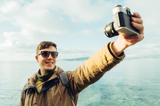 Happy man takes photographs self portrait on coastline