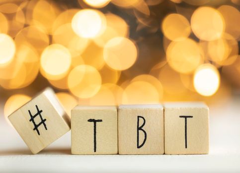 Hashtag TBT throwback Thursday written with wooden cubes with shiny bokeh background, social media concept