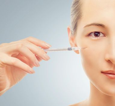 Syringe near the woman's face, cosmetic injection of wrinkles, beauty concept