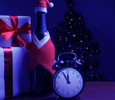 Champagne, gift boxes and the clock on the background of Christmas tree