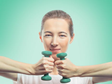Woman holds two dumbbells in front of herself on a green background