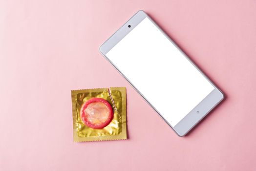 condom in wrapper pack and smart mobile phone blank screen