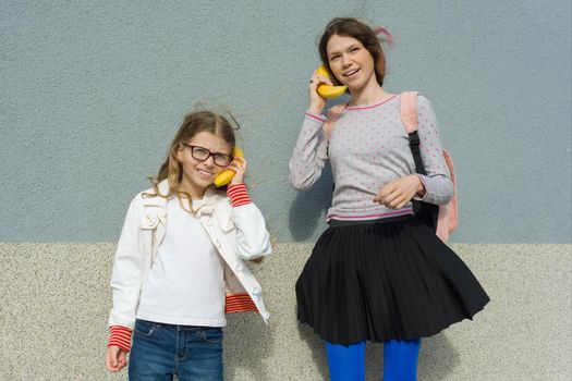 Girls teenager and child playing talking on abstract phone banana