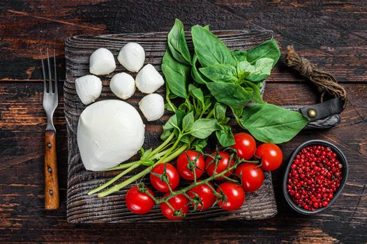 Mozzarella cheese, basil and tomato cherry on wooden board, Ingredients for Caprese salad. Dark wooden background. Top view