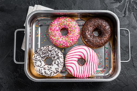 Assorted donuts with chocolate, pink glazed and sprinkles Doughnut. Black background. Top view