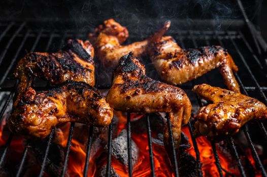 Chicken wings on barbecue, outdoor BBQ grill with fire. Top view