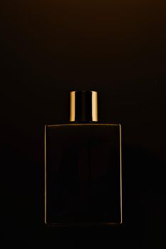 Men's fragrance of perfume or eau de toilette. Promotional photo of a black bottle on a dark background. Layout
