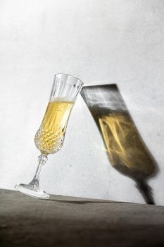 Champagne glass and long glass shadow against concrete wall