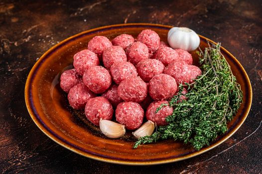 Fresh Raw meatballs from mince beef and pork meat with thyme. Dark background. Top view