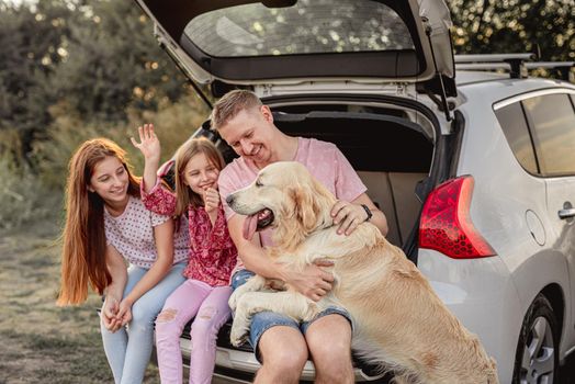Father with daughters and dog in car