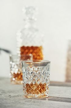Glasses of whiskey with ice cubes and carafe close up