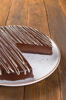 Cut chocolate cake on plate on wooden table