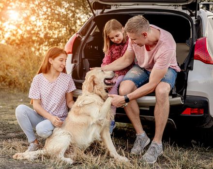 Family with dog next to open car