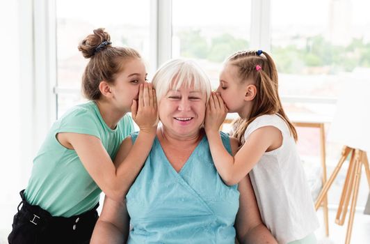 Cute granddaughters sharing secret with grandmother